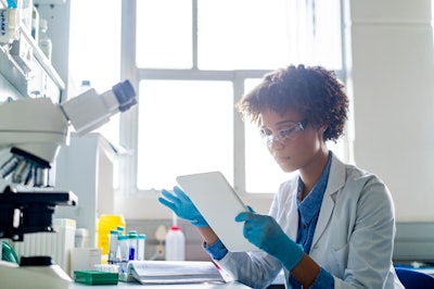 Female doctor examining notes on a tablet in a lab