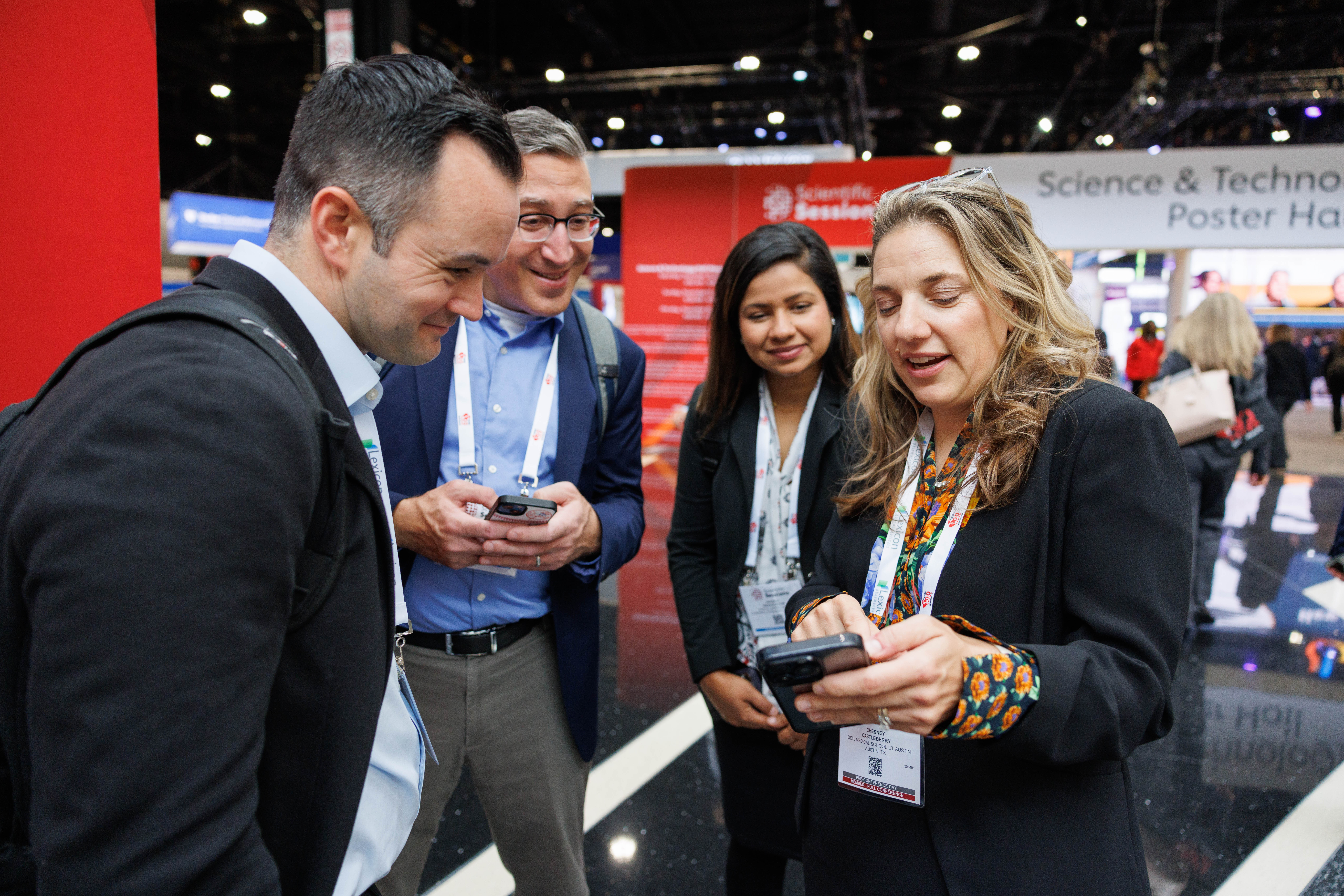Four professionals networking at a science and technology conference poster hall