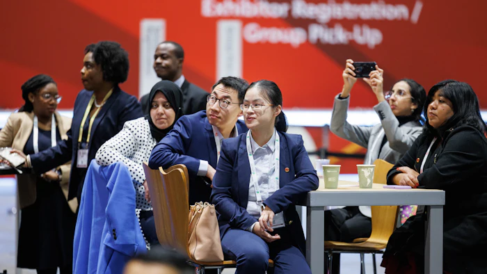 Diverse professionals gathered at conference registration area with red backdrop