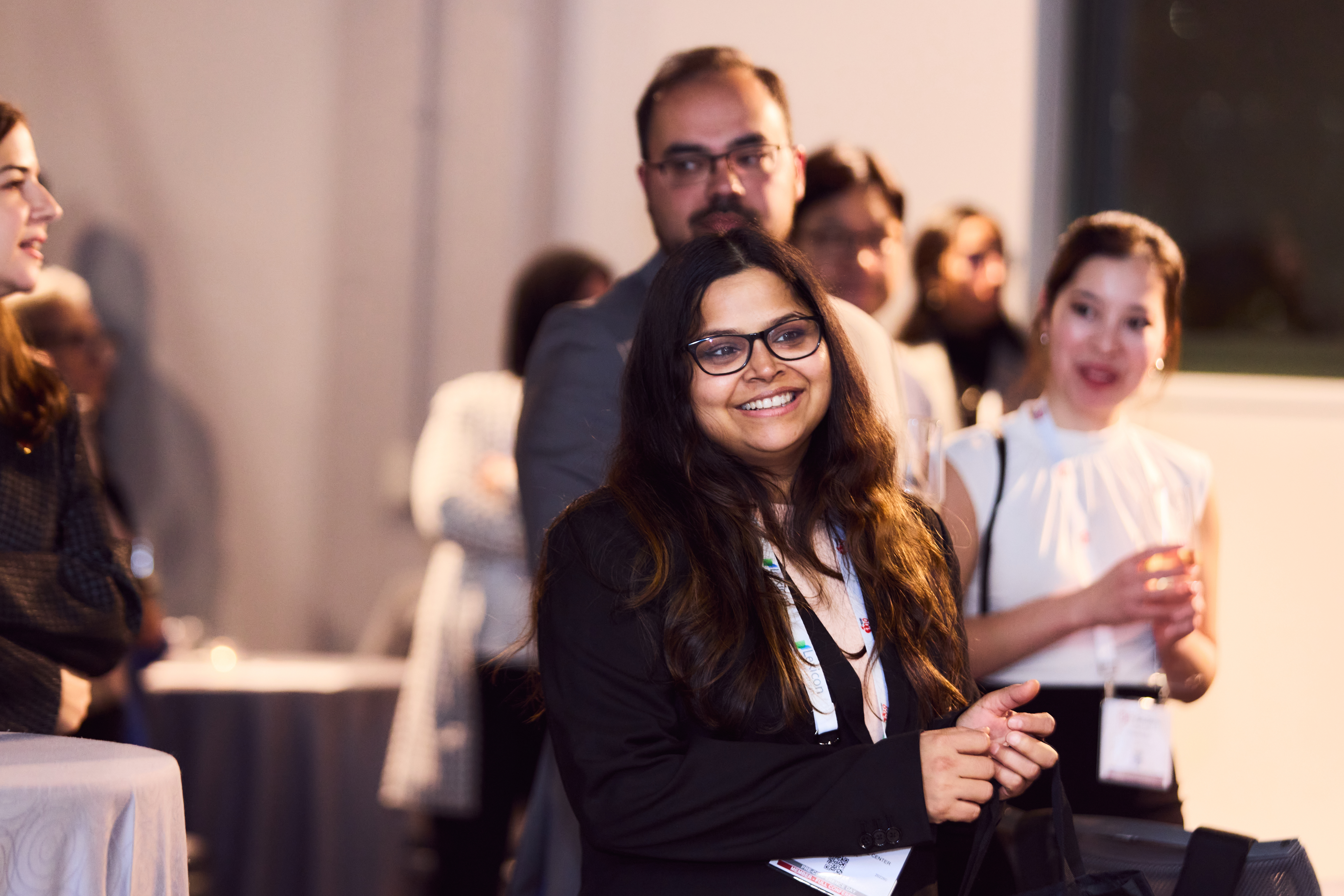 Smiling professional woman at conference with colleagues in background