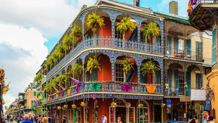 Historic French Quarter building with ornate iron balconies, hanging ferns, and colorful decorations