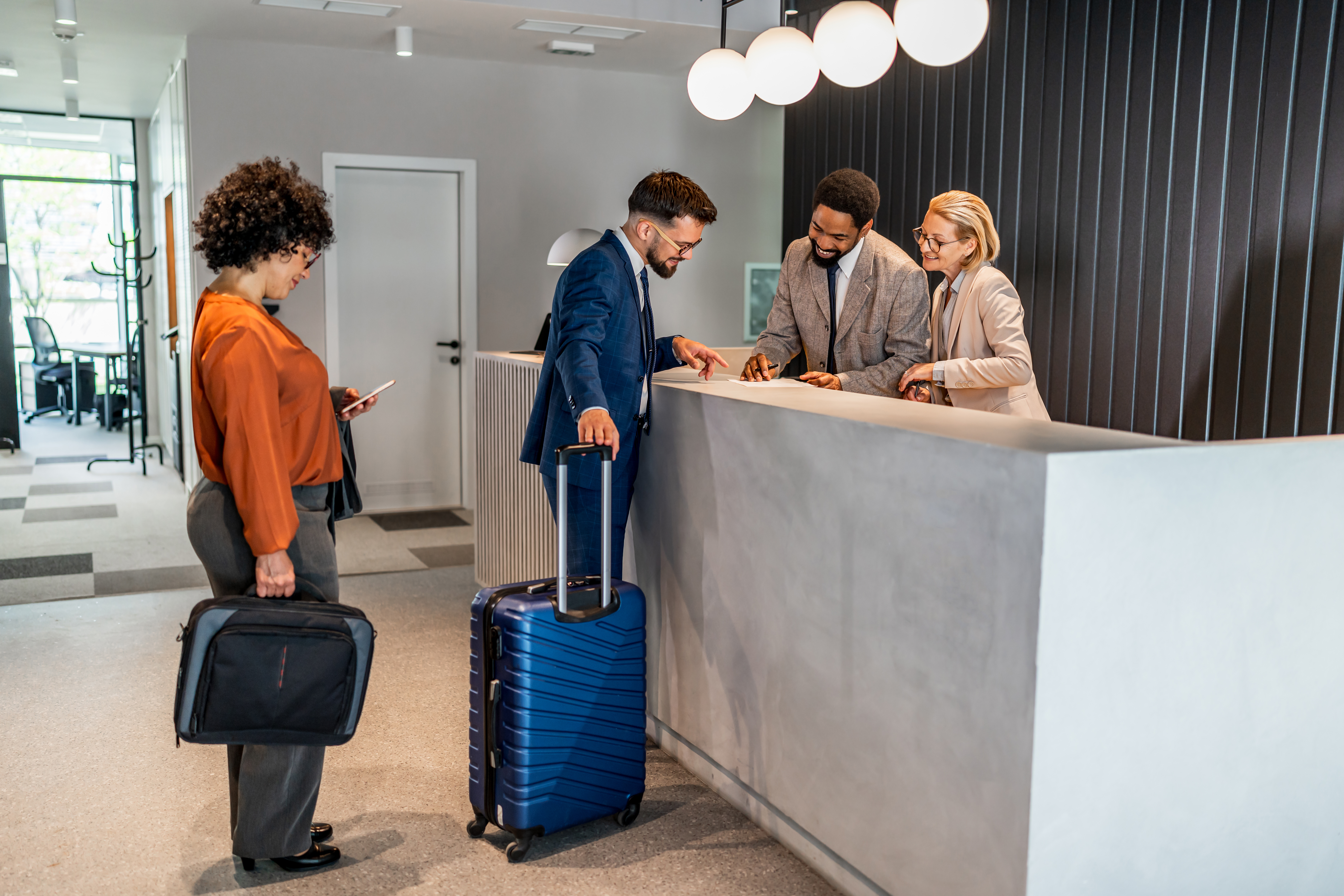 Business travelers checking in at a modern hotel reception desk with luggage