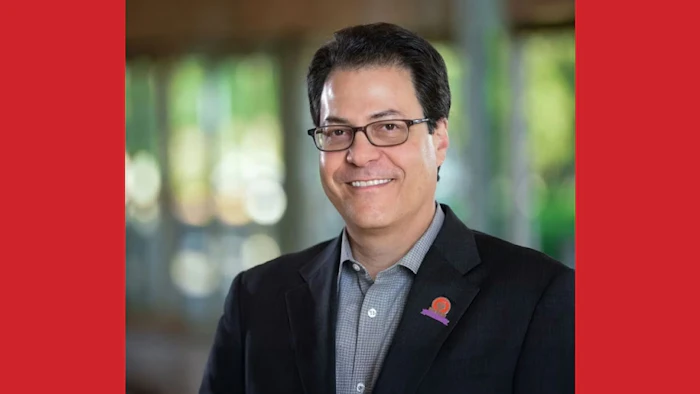 Smiling professional in black suit and glasses against blurred office background