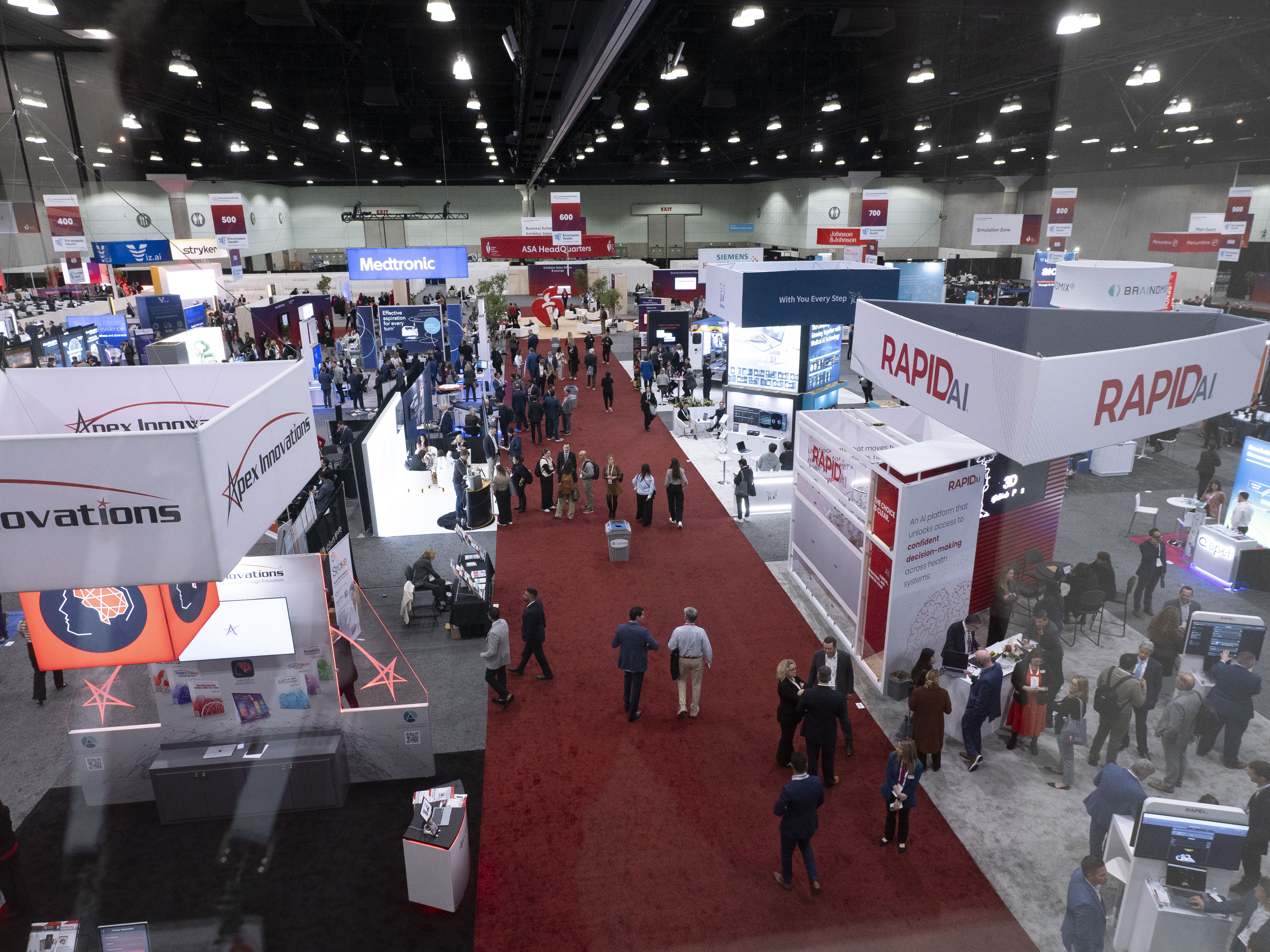 Large trade show convention with red carpet, exhibition booths, and attendees networking
