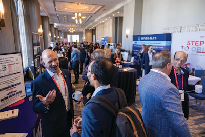 Business professionals networking at a corporate conference event with exhibition booths and branded signage