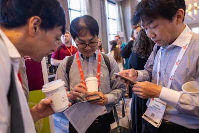 People at a conference event wearing lanyards and name badges, examining materials and networking together indoors.