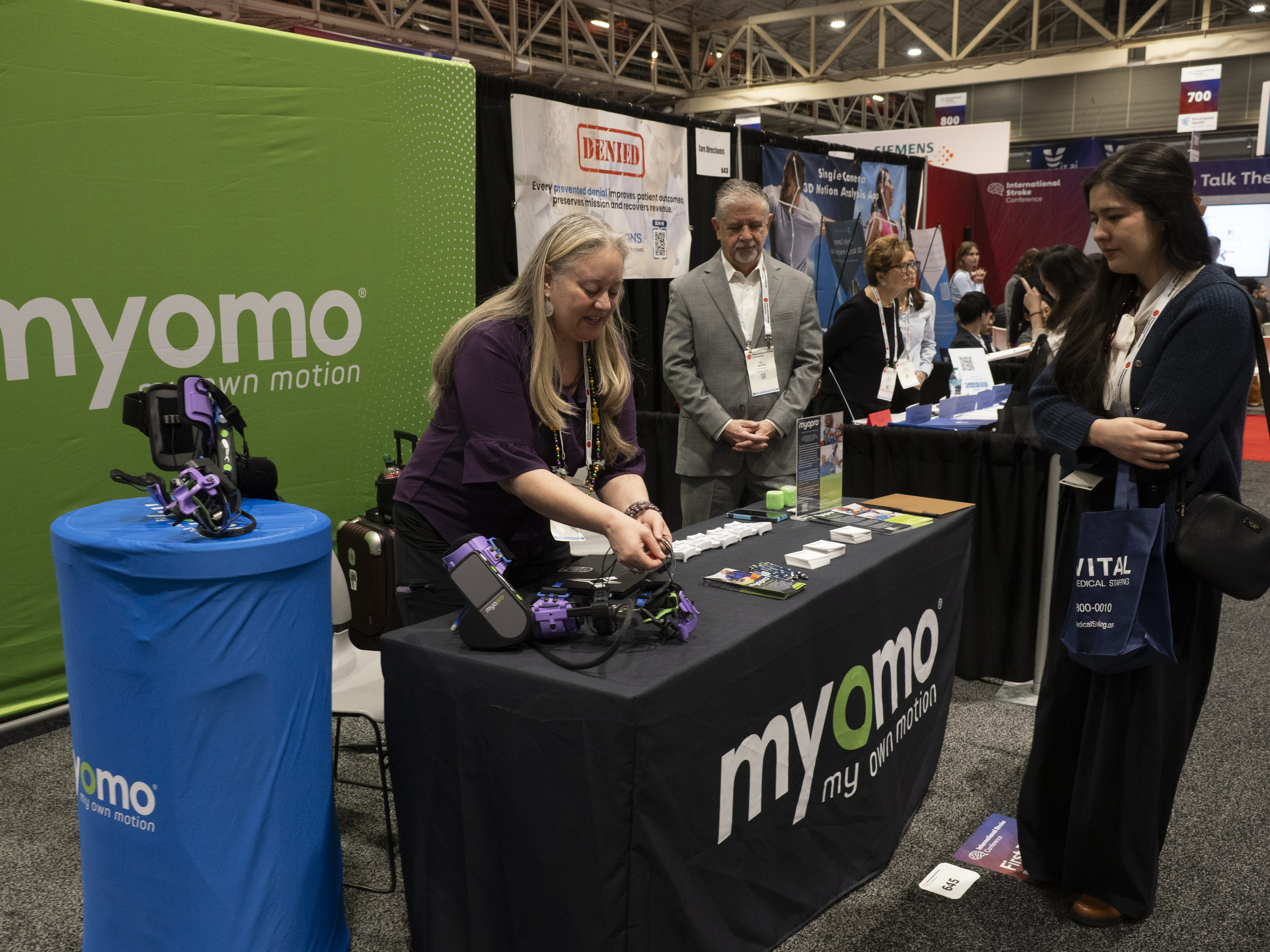Trade show booth attendees demonstrating myomo robotic motion technology at conference exhibition