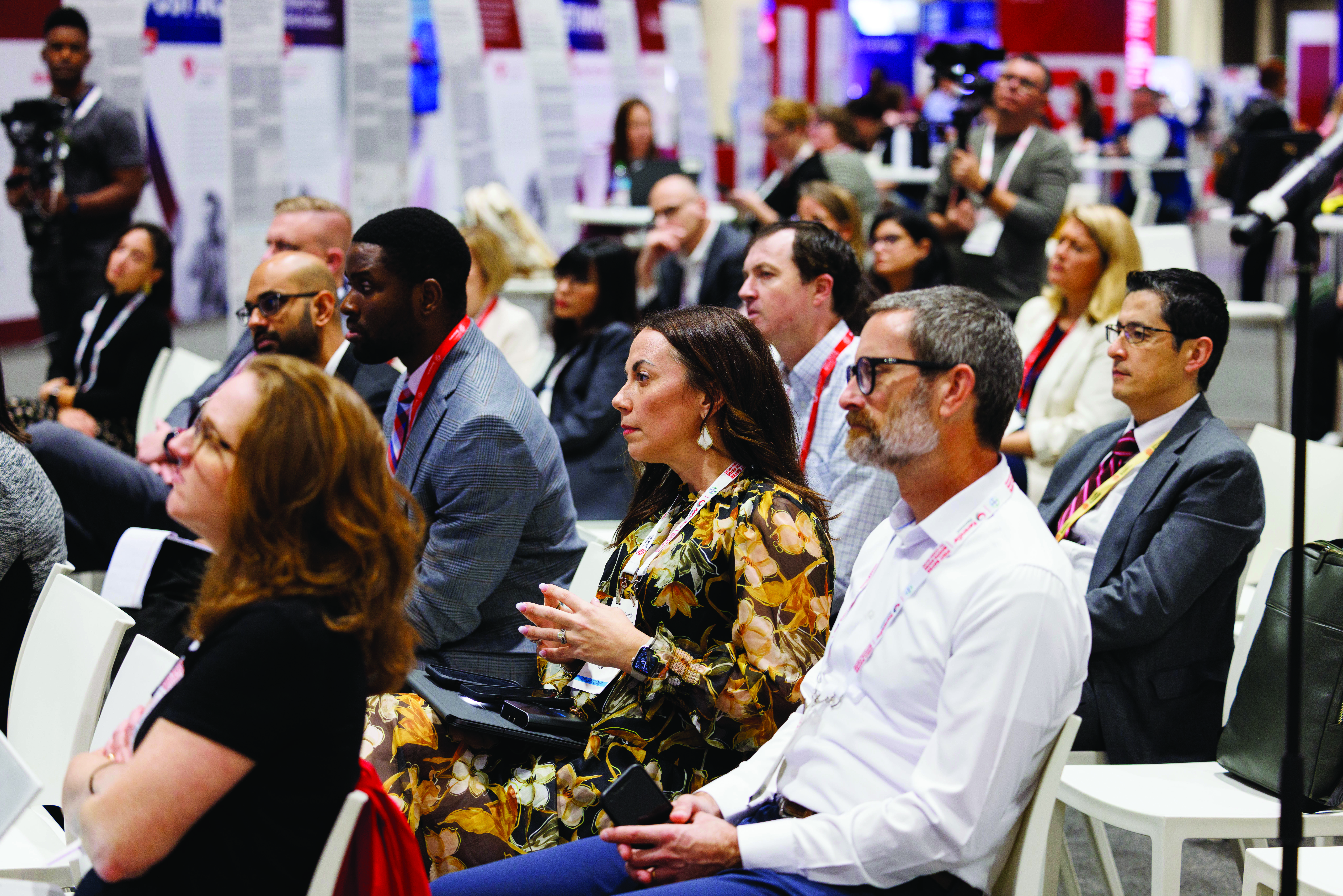 Diverse professionals networking at a conference with ID badges and lanyards in a crowded convention hall.