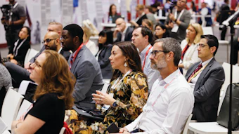 Diverse professionals networking at a conference with ID badges and lanyards in a crowded convention hall.