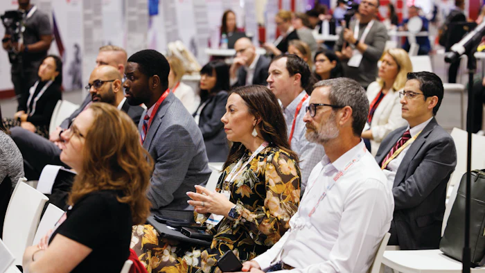Diverse professionals networking at a conference with ID badges and lanyards in a crowded convention hall.