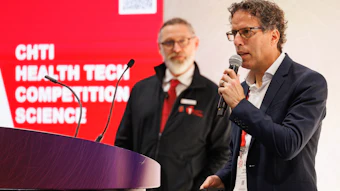 Man speaking at podium during CHTI Health Tech Competition Science event with colleague in background