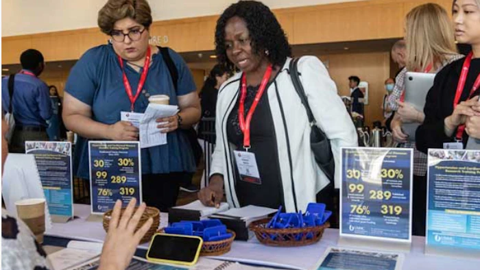 Conference attendees at an information booth discussing program statistics and materials